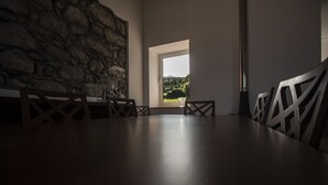 Una habitación con pared de piedra, un ventanal grande y una mesa con sillas.