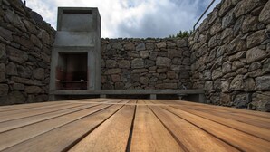 Un espacio al aire libre con paredes de piedra, una mesa de madera y una chimenea de piedra.