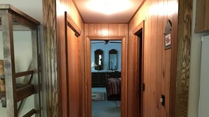 Un couloir en bois mène à une chambre à coucher qui contient un lit et une commode.