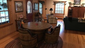 Un intérieur en bois avec une table de salle à manger ronde, des fauteuils en cuir, un canapé et un téléviseur.
