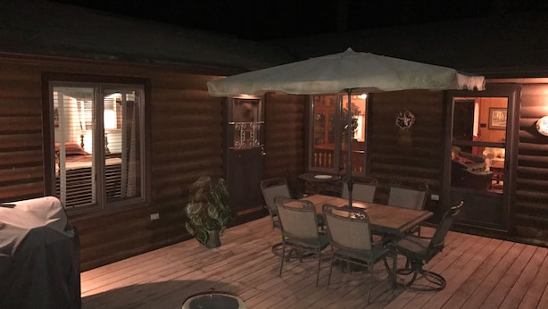 Une terrasse en bois avec une table et des chaises, un parasol et une plante en pot.