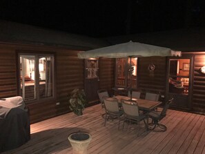 Une terrasse en bois avec une table et des chaises, un parasol et une plante en pot.