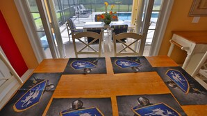 Un coin repas avec une table dressée pour quatre personnes, agrémentée d’un motif en forme d’écu sur le dessus de table.