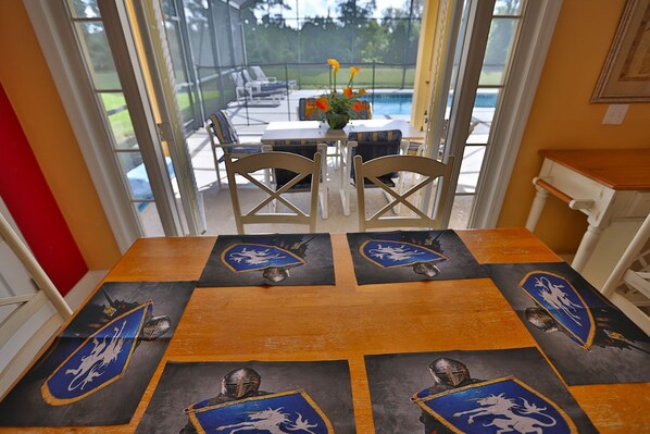 A dining area with a table set for four, featuring a shield emblem design on the tablecloth.