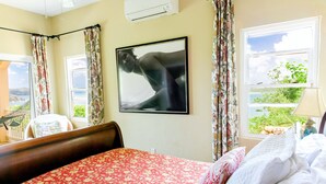 Une chambre à coucher avec un lit, un hamac, une fenêtre avec des rideaux et un climatiseur fixé au mur.