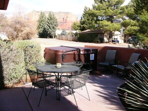 An outdoor patio with a round table and chairs, a barbecue grill, and a covered seating area.
