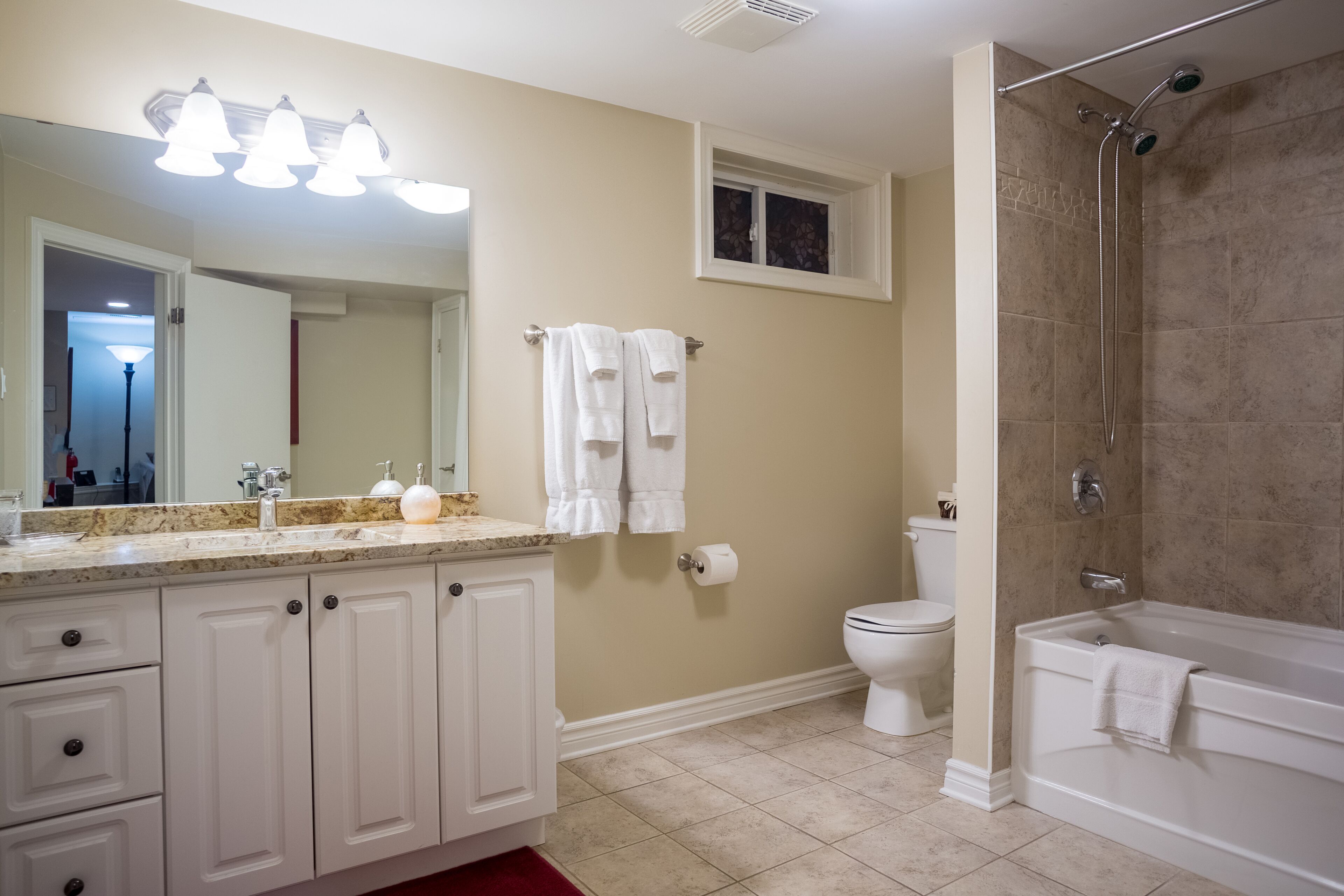 A bathroom with a sink, mirror, towel rack, toilet, and shower.