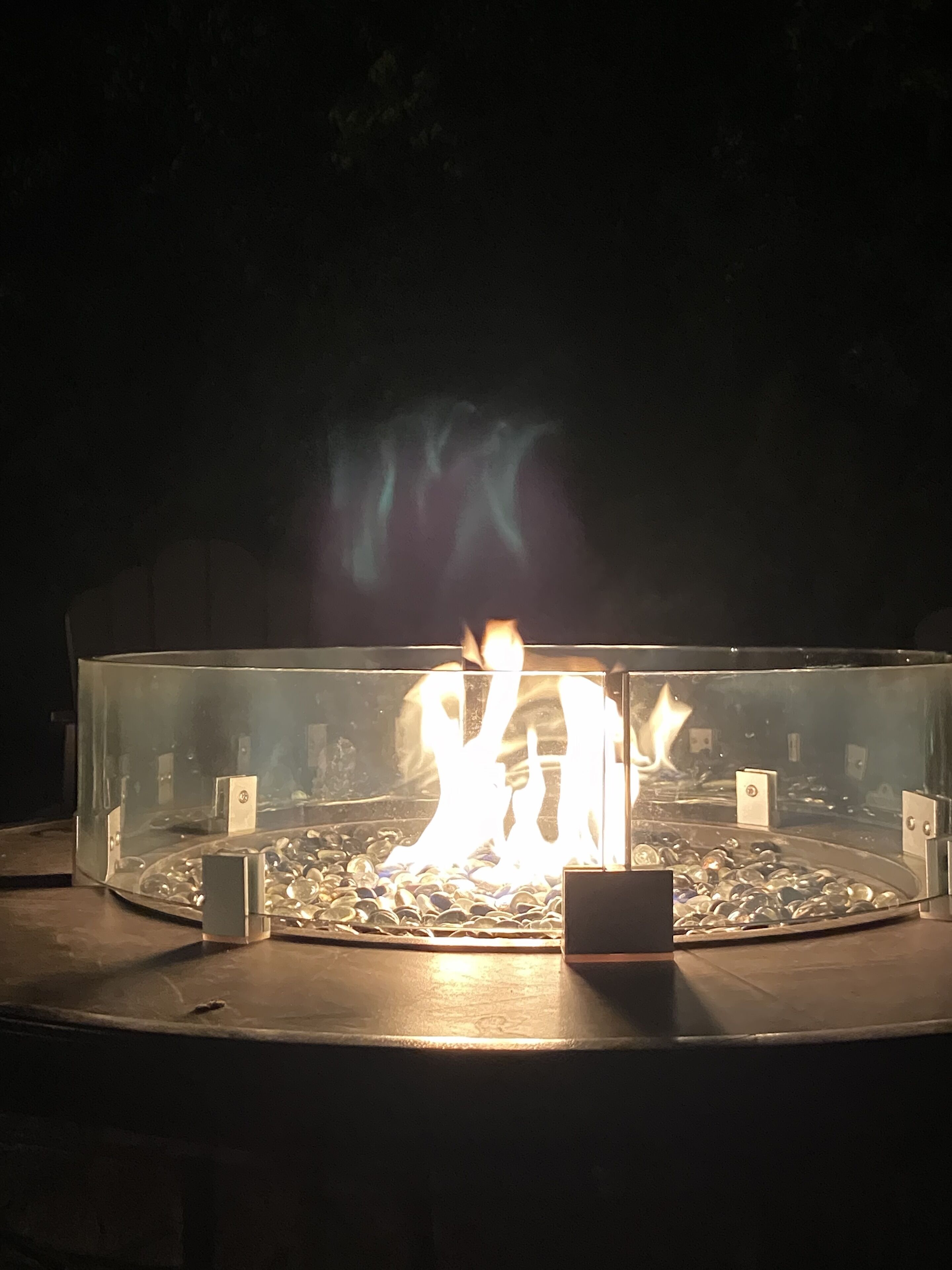 Un elemento decorativo con fuoco, racchiuso in vetro e circondato da un anello di pietre.