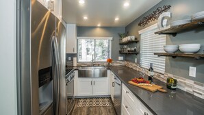 Una cocina moderna con electrodomésticos de acero inoxidable, armarios blancos y piso de madera.