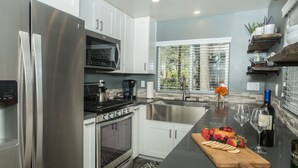 Una cocina moderna con electrodomésticos de acero inoxidable, horno empotrado y una isla grande con una bandeja de frutas.