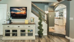 Una sala de estar con un aparador de madera, un televisor y una escalera que lleva a otra habitación.