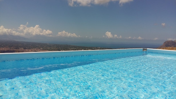 Ein klares, blaues Schwimmbecken mit Blick auf eine ferne Stadtlandschaft und Berge.