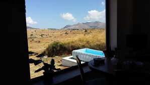 Ein Zimmer mit Blick auf eine gebirgige Landschaft, einem kleinen Pool und einem Essbereich mit Tisch und Stühlen.