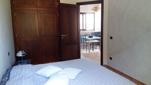Ein Schlafzimmer mit Bett, einem Holzschrank und Blick auf eine Terrasse.