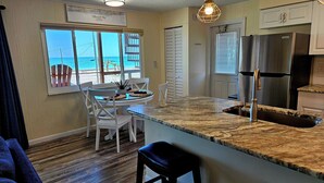 A kitchen with a large island, a dining area with a view of the beach, and a modern stainless steel refrigerator. - 30 Seconds to Beach Path! All inclusive! Kayaks, SUP's, Bikes & so much more!!! (Englwood)