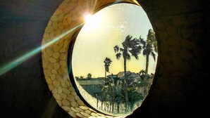 A round mirror with a reflective surface, surrounded by a textured frame.