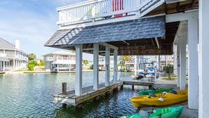 A waterfront property with a dock, boats, and a covered area with railings.