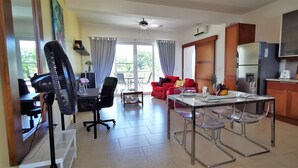 Uma sala de estar moderna com área de jantar, cozinha e uma varanda com cortinas.