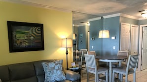 A living room with a gray sofa, a floral pillow, a side table with a lamp, and a framed picture on the wall. - Pier Park and Aaron Bissant Park within walking distance!   (Panama City Beach)