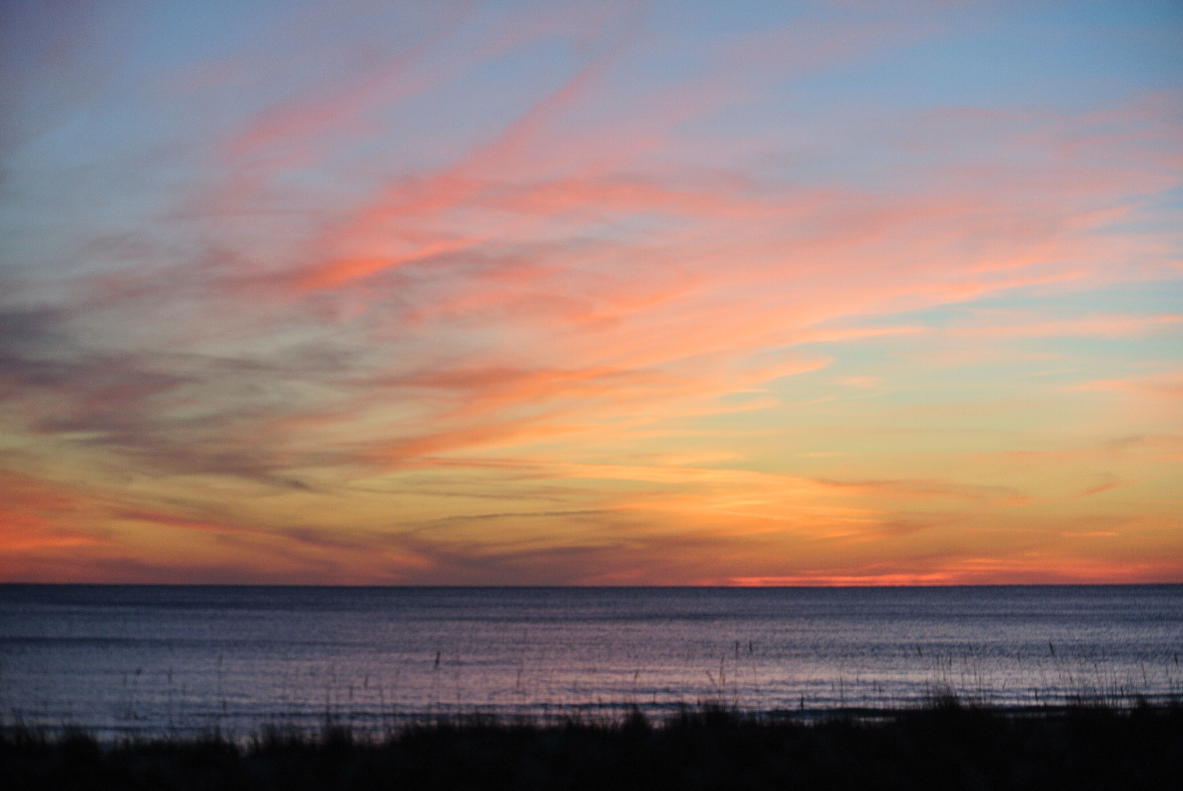 Un coucher de soleil sur une mer calme, avec un horizon dégagé.