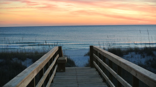 A wooden boardwalk leading to a beach with a sunset in the background. - Pier Park and Aaron Bissant Park within walking distance!   (Panama City Beach)