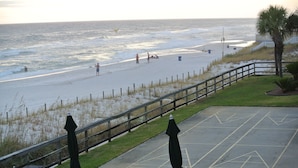 A beach view with a wooden fence, umbrellas, and a parking area with yellow markings. - Pier Park and Aaron Bissant Park within walking distance!   (Panama City Beach)