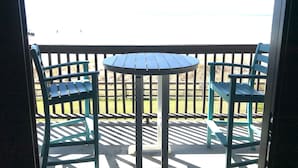 A balcony with a table and chairs, overlooking a grassy area. - Pier Park and Aaron Bissant Park within walking distance!   (Panama City Beach)