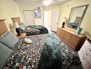 Una camera da letto con due letti, una cassettiera, uno specchio e una porta.