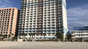 Un hotel moderno de gran altura con varios balcones, cerca de la playa.