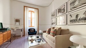 A living room with a sofa, coffee table, and a dining area with a cabinet and chair. - Live Like a Local in a Artful Apartment near the Colosseum (rome)