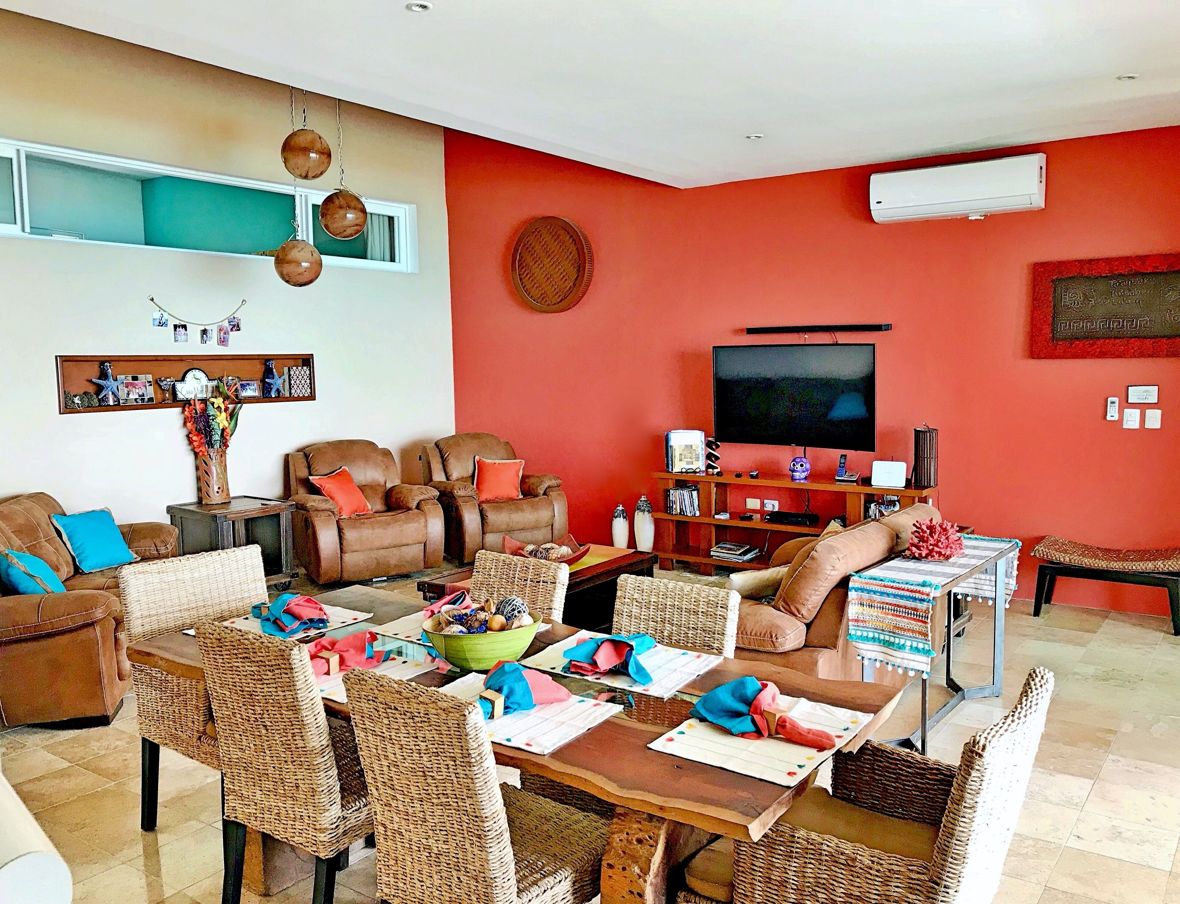 A living room with a television, seating area, and a dining table.