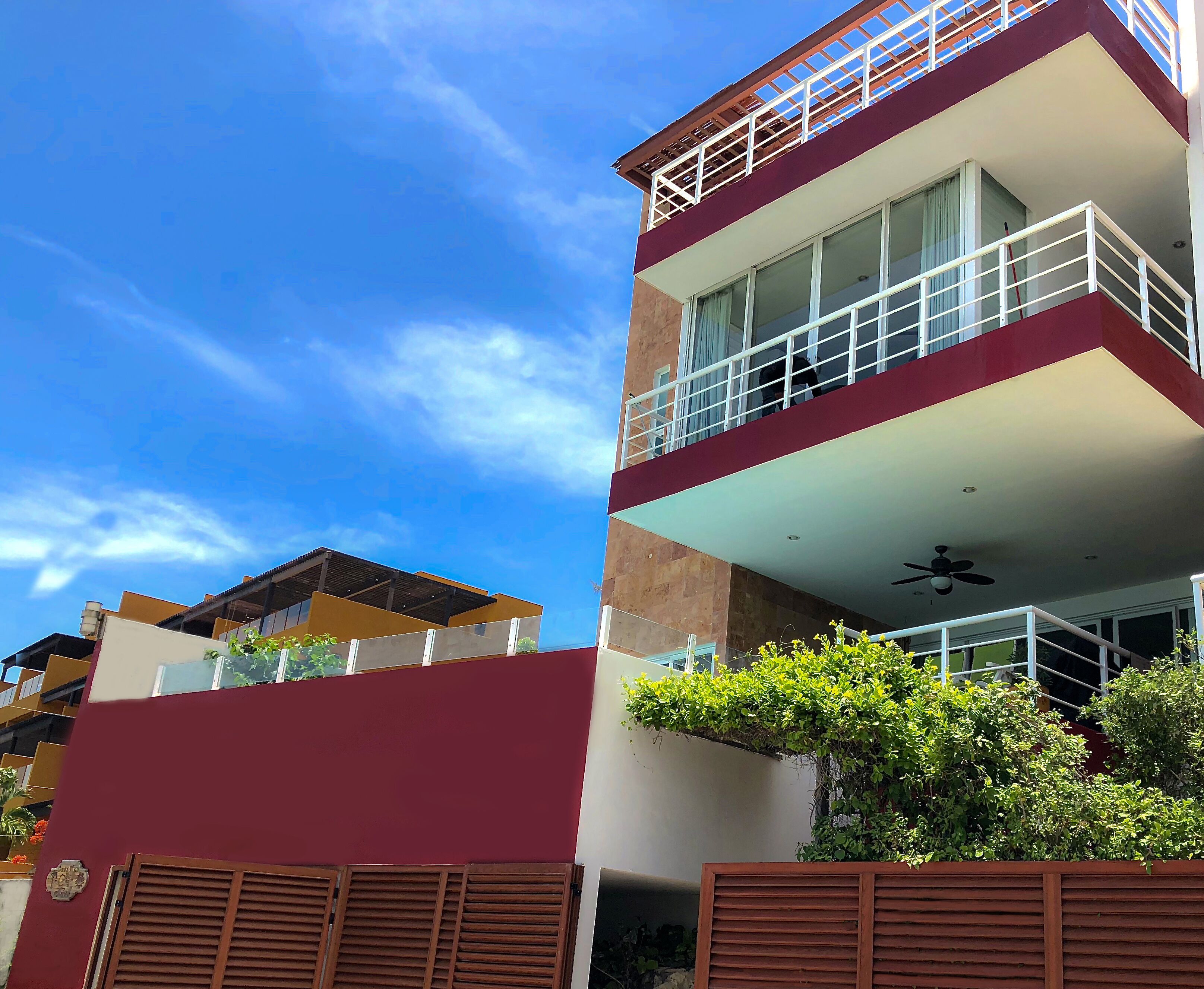 A multi-story building with balconies, a flat roof, and a clear blue sky.