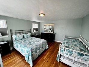 Un dormitorio con cama, cómoda, espejo y mesita de noche.
