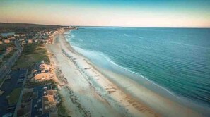 Vista aérea de una zona costera con playa, casas y una carretera.