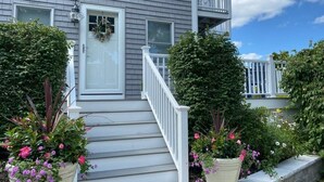 Una casa de dos pisos con un porche delantero, barandas blancas y un pequeño balcón.