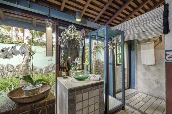 A bathroom with a large mirror, a glass bowl sink, and a potted plant.