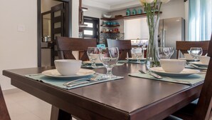 A dining table set with white bowls, wine glasses, and a vase of white flowers. - Nautical Homes 3 Ocean Front/View, Free Wifi, A/C, Hot Tub, BBQ Grill. Balcony (Montego bay)