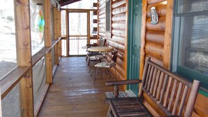 Une cabane en bois dotée d’une véranda, de bancs en bois et d’une table avec des chaises.