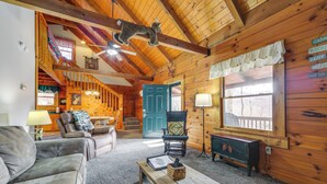 L’intérieur d’un chalet accueillant, avec un plafond en bois, un canapé, un fauteuil, une table et une porte bleue.