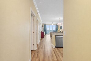 A hallway leading to a kitchen with a view of the ocean. - Last minute availability in early August gulf front with prepaid beach chairs (Panama City Beach)