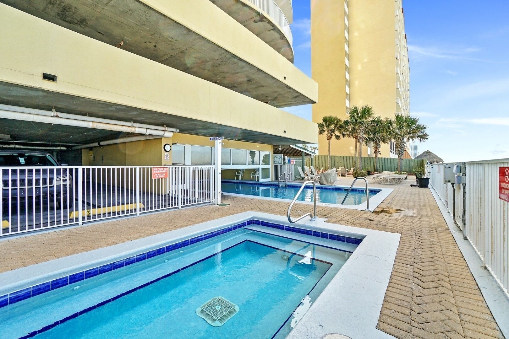 Un área de piscina en la azotea, con piscina, sillas de descanso y un edificio al fondo.