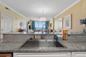 A kitchen with granite countertops, a stainless steel sink, and a ceiling fan. - Last minute availability in early August gulf front with prepaid beach chairs (Panama City Beach)