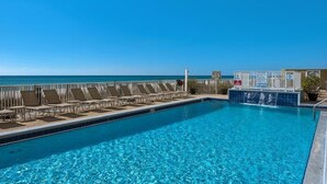 A pool with lounge chairs and a view of the ocean.