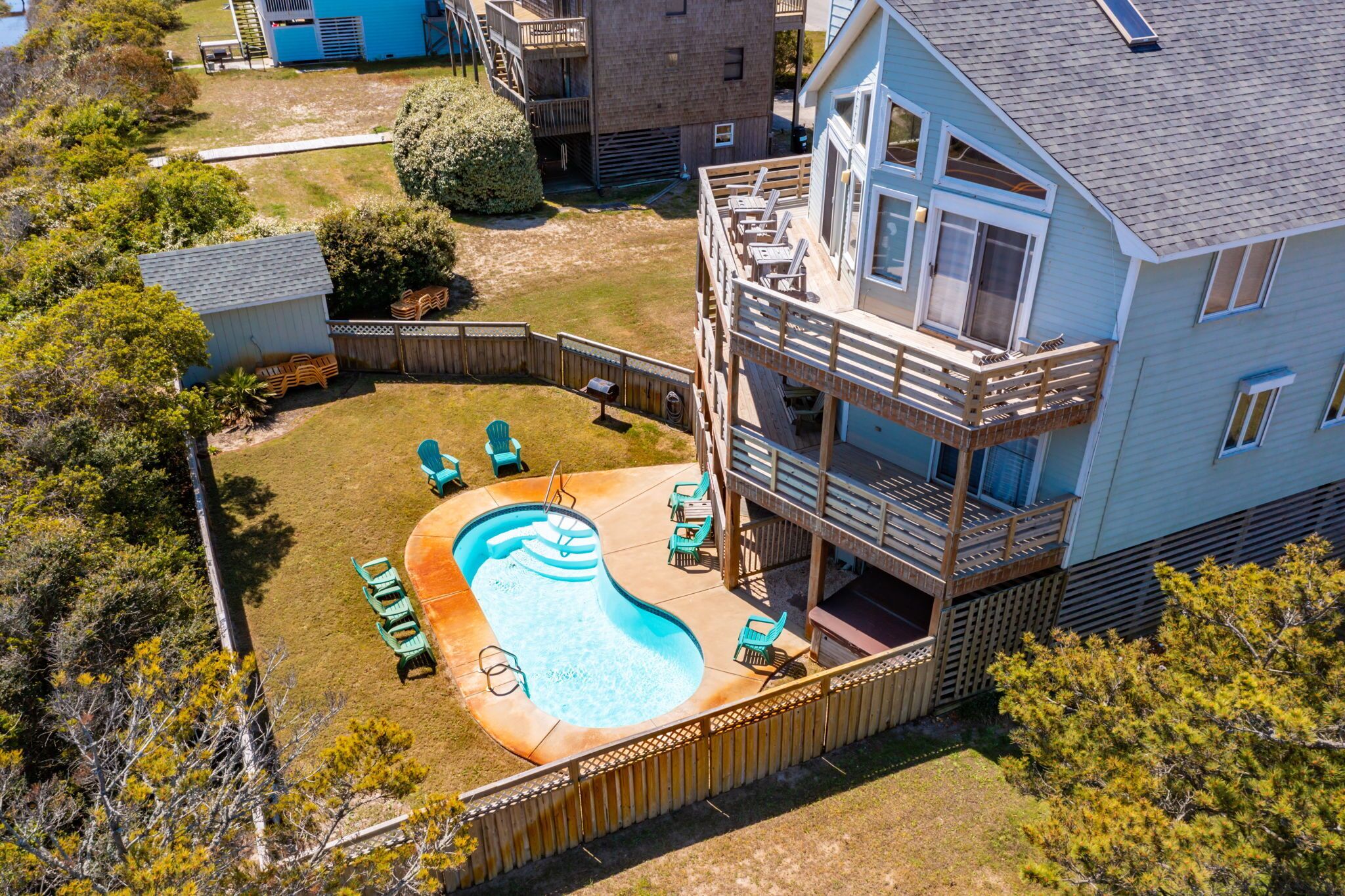 A residential property with a swimming pool, outdoor seating, and a multi-level deck.