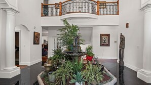 A spacious foyer with a central fountain, surrounded by various plants and a decorative statue. - Mansion - 20 mins to Airport /  20 mins  to Downtown Atlanta & Buckhead (Ellenwood)