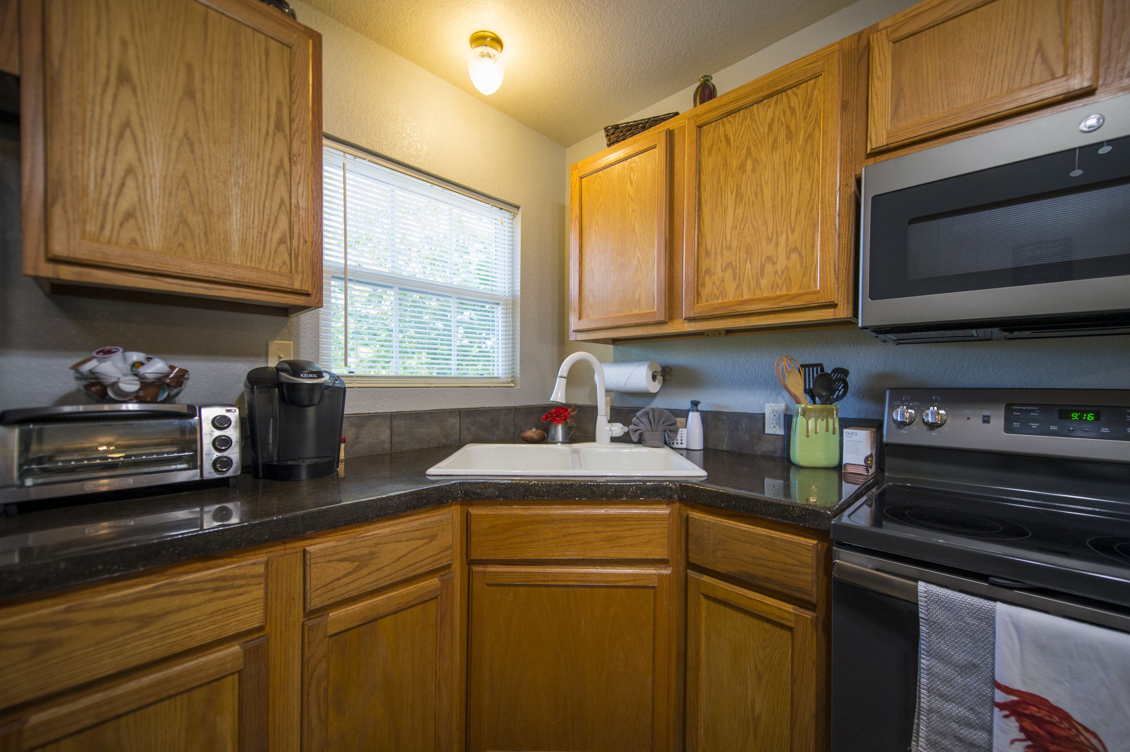 A kitchen with wooden cabinets, a microwave, a toaster, and a sink.