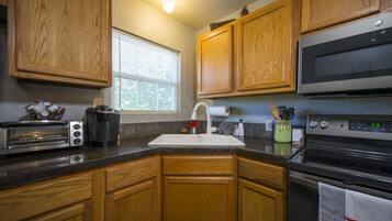 A kitchen with wooden cabinets, a microwave, a toaster, and a sink.