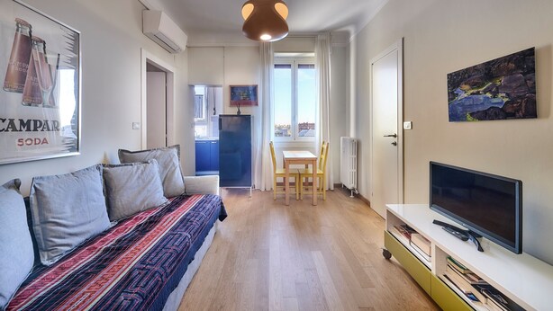 Un salon moderne avec un canapé, un téléviseur et un coin repas.