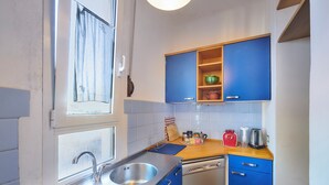 Une cuisine équipée d’un évier à deux bacs, d’un lave-vaisselle et de meubles de rangement bleus.