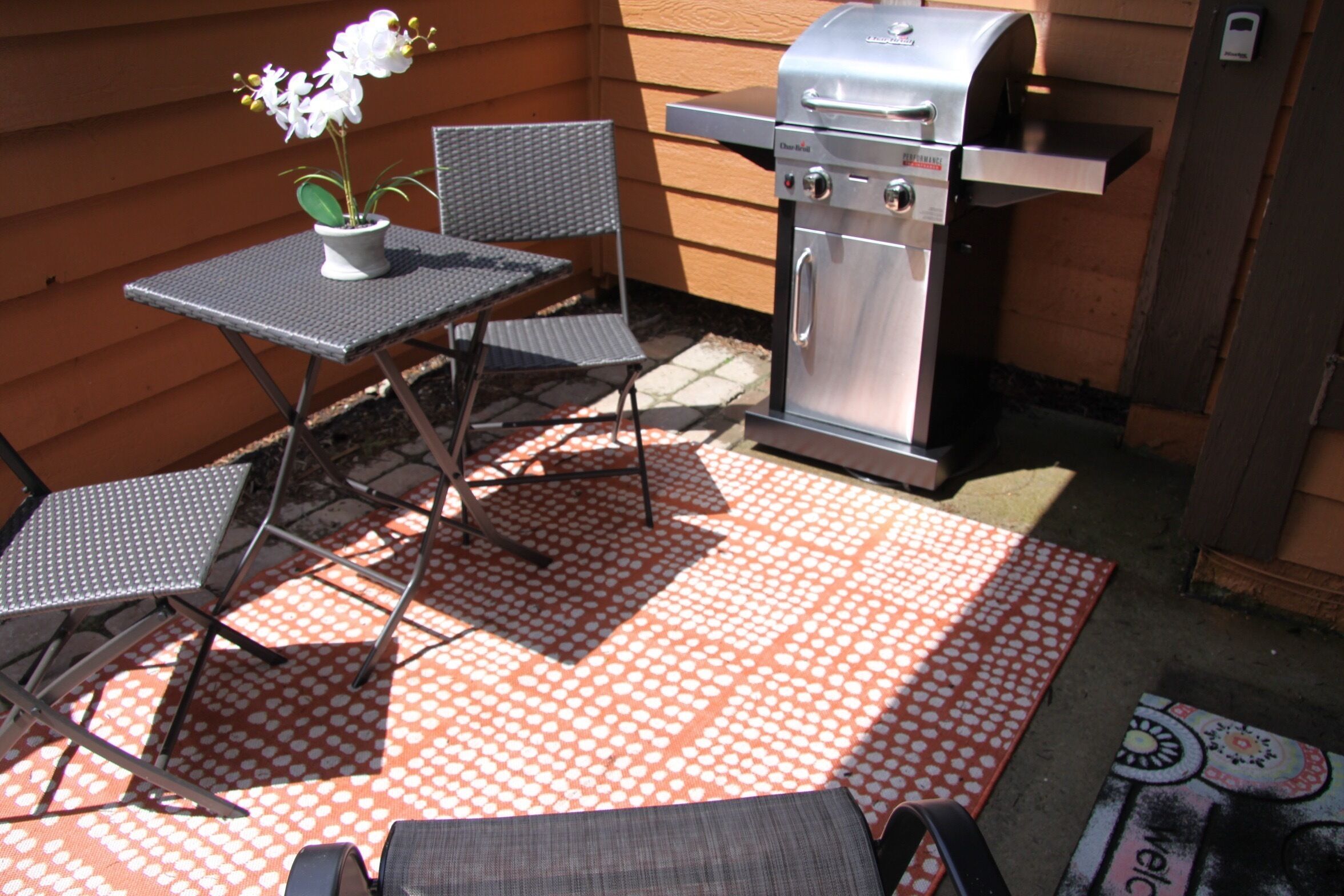 Eine Terrasse im Freien mit Grill, Stühlen und Tisch.